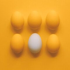 Eggs on yellow background. One white egg and five yellow eggs.