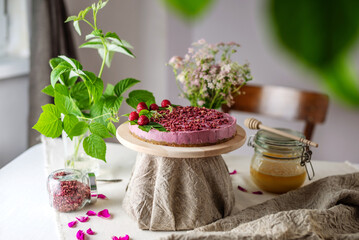 Appetizing raw mousse cake with raspberries, decorated with berries and green leaves. Concept of delicious and healthy summer desserts