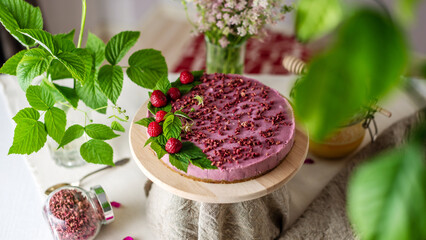 Appetizing raw mousse cake with raspberries, decorated with berries and green leaves. Concept of delicious and healthy summer desserts