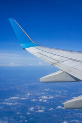 Obraz premium The plane is flying in the sky, the blue sky and white clouds outside the window 