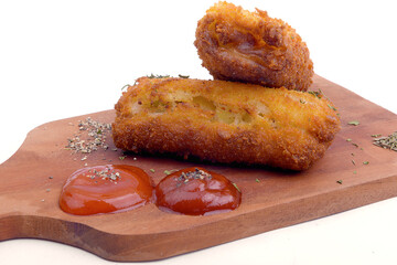 Croquette with tomato sauce and chili sauce on wooden board