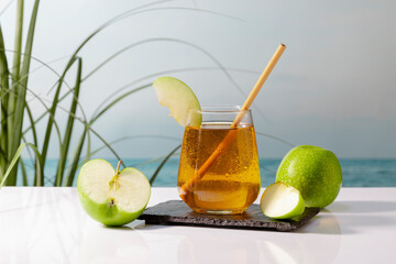 Fototapeta premium Delicious glass of apple juice with a straw and an apple slice on a dark plate.healthy food concept