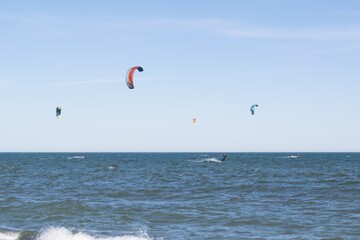 Group of people kitesurfing on the waves of the sea on a sunny clear day