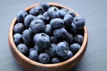  Blueberry berry in a wooden round cup close-up on a black slate background.Healthy  natural dessert and snack.Vegetarian and vegan food. blueberries season.