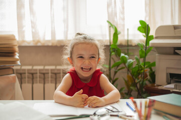 The child sits at the table and laughs because the teacher told a funny story. Preschool education. International Literacy Day. Education and science.