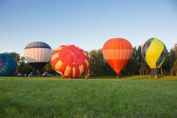Obraz premium Kyiv, Ukraine - 06/26/2020: Hot air balloons in clear sky over forest. Colorful balloons on aerial landscape background. Summer leisure. Hot air balloons in flight in morning. Balloons festival.
