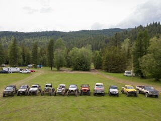Aerial shot of off-road vehicles in a grass field near trees