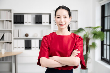 Confidence team leader. Young women asian owner startup business looking camera with smile while his colleagues working in the background