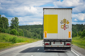 A  truck with the national flag of Vatican. depicted on the back door carries goods to another...