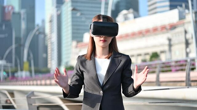 Business Asian woman wearing Virtual reality glasses headset in city. pretend to watch the virtual world of future technology in city. Augmented Reality