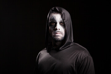 Young man looking serious into the camera dressed up like grim reaper. Halloween costume.