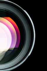 The camera lens. Close-up of the camera lens on an isolated black background. Optics. Vertical photo