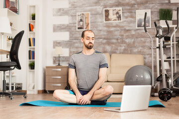 Fit man learning yoga from online course during global pandemic.