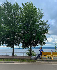 Naklejka premium Photo of a girl with a bicycle, who is resting after doing sports on a bench