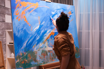 Painting with bright colors on large canvas in art workshop. Modern artwork paint on canvas,...