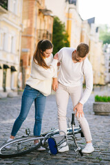 Man with injury and woman standing over bicycle.