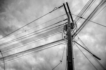 The electric pole with its interlaced power lines,stood out against On cloud sky background