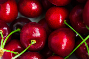 A lot of fresh sweet cherry fruit berries with water drops, close up. Pile of ripe cherries. Large collection of fresh red cherries. Ripe cherries texture background