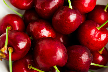 A lot of fresh sweet cherry fruit berries with water drops, close up. Pile of ripe cherries. Large collection of fresh red cherries. Ripe cherries texture background