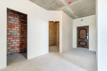 The hallway in an apartment in a new building without decoration. The new flat with the empty doorways and the white plastered walls