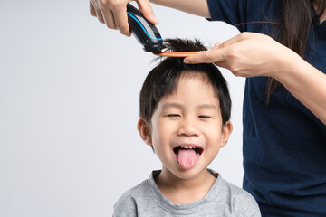 Asian boy got hair cut at home by his mother with electric cordless clippers