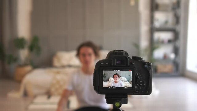 A young attractive male student records a video blog on a camera from the living room. Social networking, The Social Media Blog