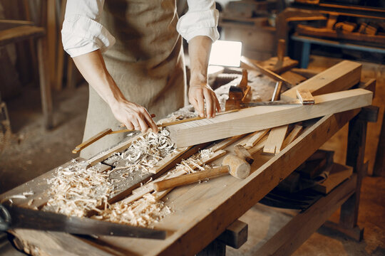 Man working with a wood. Carpenter in a white shirt. Worker measures a board