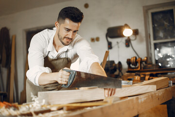 Man working with a wood. Carpenter in a white shirt