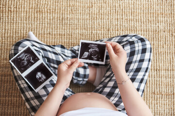 Top view of a pregnant woman holding ultrasound image. Concept of pregnancy, health care,...