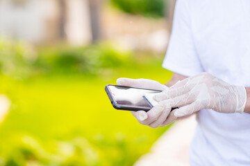 Senior man cleans screen of a mobile phone with cotton wool and sanitizer during flu virus outbreak, coronavirus epidemic