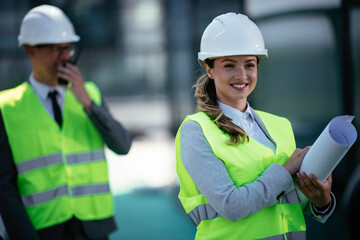 Portrait of businesswoman in factory. Young female architect with helmet in suit.	