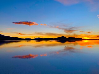 Fototapeta na wymiar Amazing bright sunset on the Saline lake in Salar de uyuni, Bolivia. Summer colours and incredible stunning view.