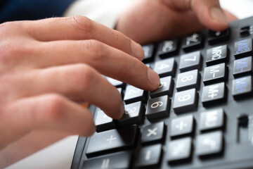 Male hand with a calculator and pen, business graph and chart.