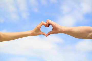 Love, friendship concept. Girl and male hand in heart form love blue sky. Female and man hands in...