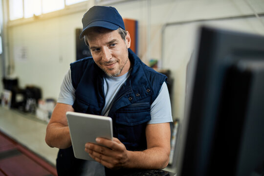 Smiling Mechanic Using Digital Tablet In Auto Repair Shop.