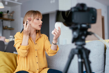 Female vlogger recording makeup tutorial for her channel. Young beautiful woman recording make up...