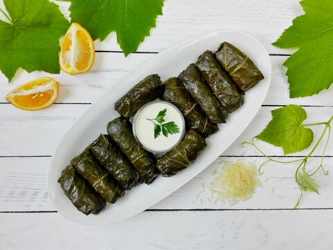 Delicious dolma (sarma) stuffed grape leaves & rice, white yogurt sauce. Lebanese dolma sarma on plate. Lebanon turkish greek middle eastern cuisine. Dinner food dolmadakia or dolma. Yaprak sarma 
