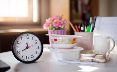 Close up of clock before lunch with food box from delivery online on desk