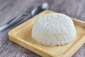 Steamed rice, cooked rice with spoon in wooden plate on grey wooden background