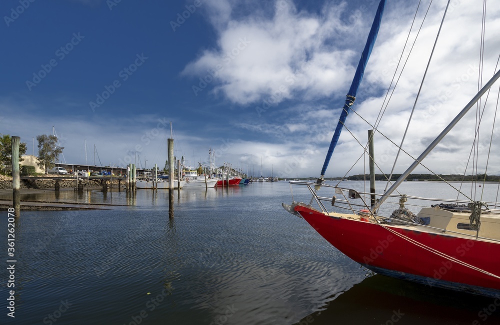 Sticker eye-level shot of sailboats in a port under the blue sky in tin can bay, queensland, australia