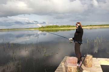 Fototapeta na wymiar Woman fishing on wooden bridge at Seliger Lake