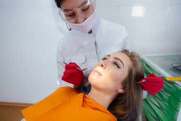 A professional dentist performs treatment and examination of the patient's oral cavity in close-up....