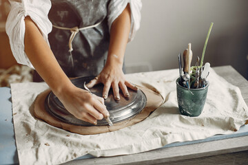 Woman in a pottery. Master make a dishes. Artist works with a clay