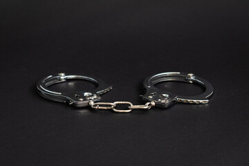 Fototapeta na wymiar Steel handcuffs on a black background. Close-up. Police handcuffs. Criminal, corruption concept