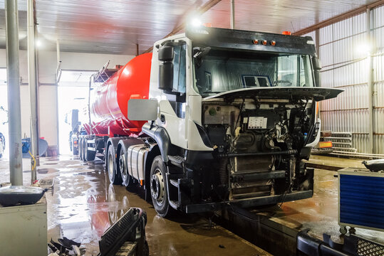 Oil truck with a red tank above the inspection pit, at a service station