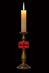 Burning stearin candle on a bronze candlestick. Isolated on a black background