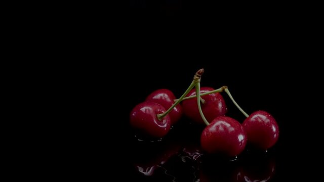 Cherry slow motion closeup falling in water with Splash droplets on black background macro shot cooking video