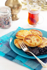 Cheese cakes on blue plate with jam and tea