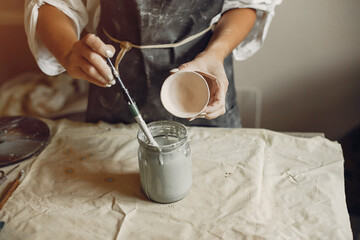 Woman in a pottery. Master make a dishes. Artist works with a clay