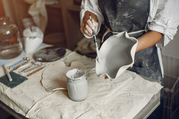 Woman in a pottery. Master make a dishes. Artist works with a clay